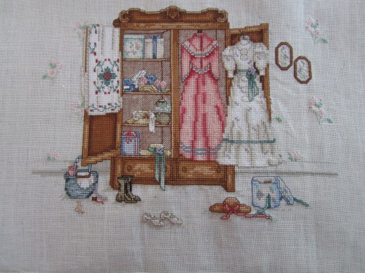 Cross stitch embroidery of antique wardrobe with dresses etc.